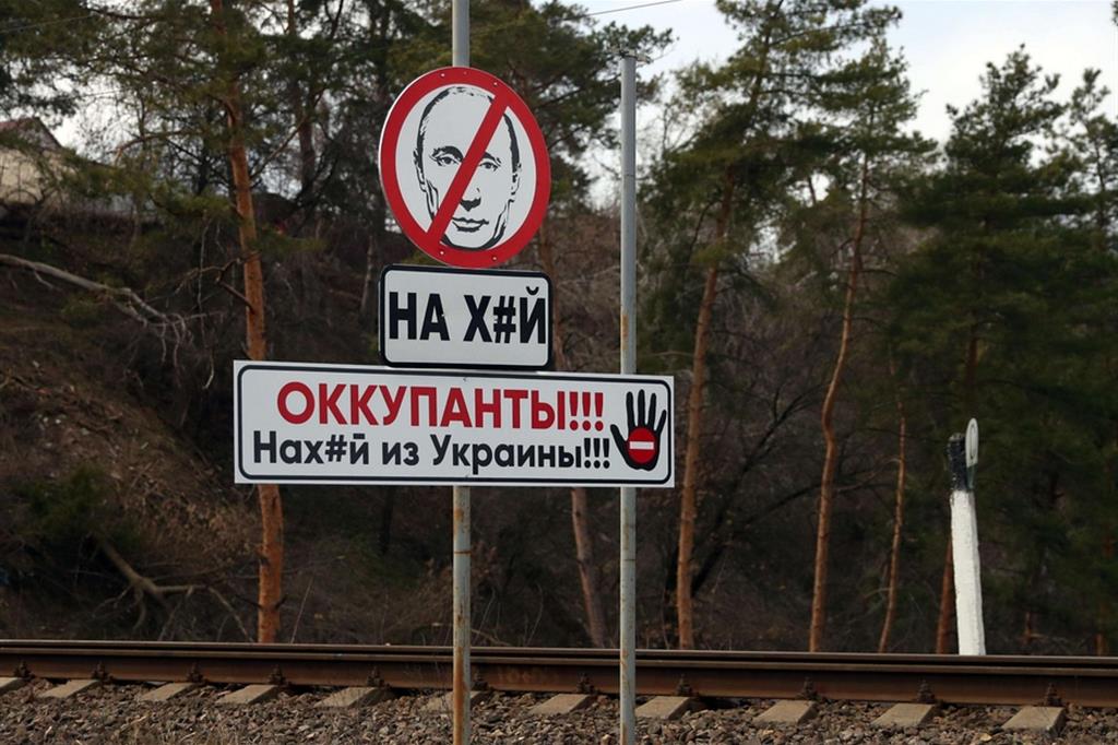 Un cartello stradale con una immagine dell presidente russo Vladimir Putin in cui si legge: "Occupanti, fuori dall'Ucraina", è apparso in un posto di blocco ucraino vicino a Cherkasy, dove la popolazione si prepara a resistere all'offensiva dal sud - Ansa/EPA/NUNO VEIGA