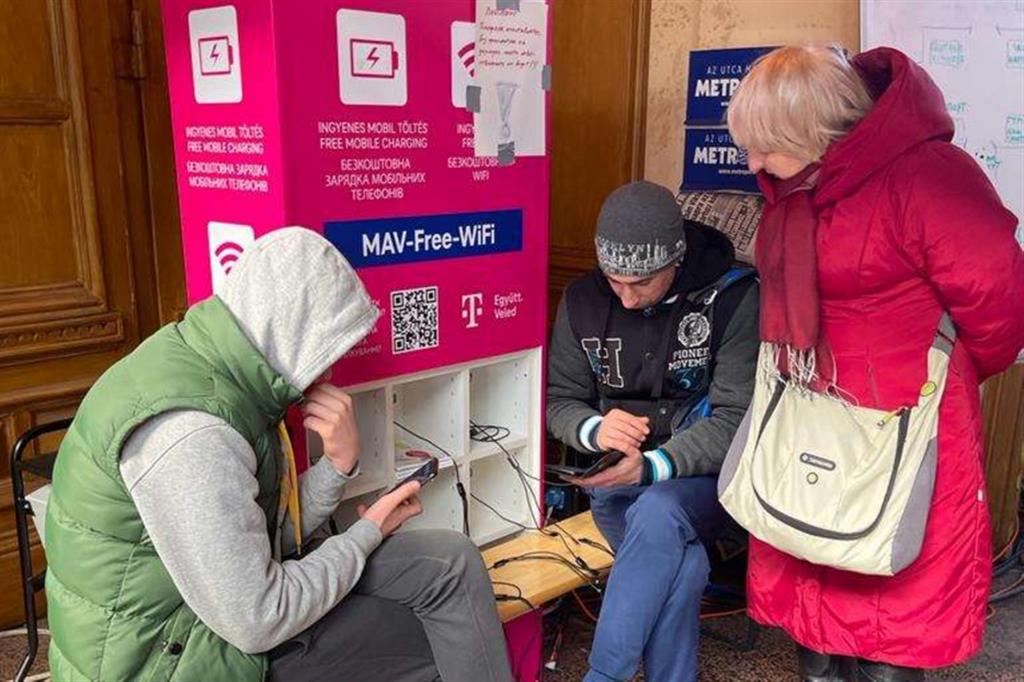 Profughi ucraini utilizzano i loro smartphone grazie a una colonnina di ricarica che offre anche il wifi libero