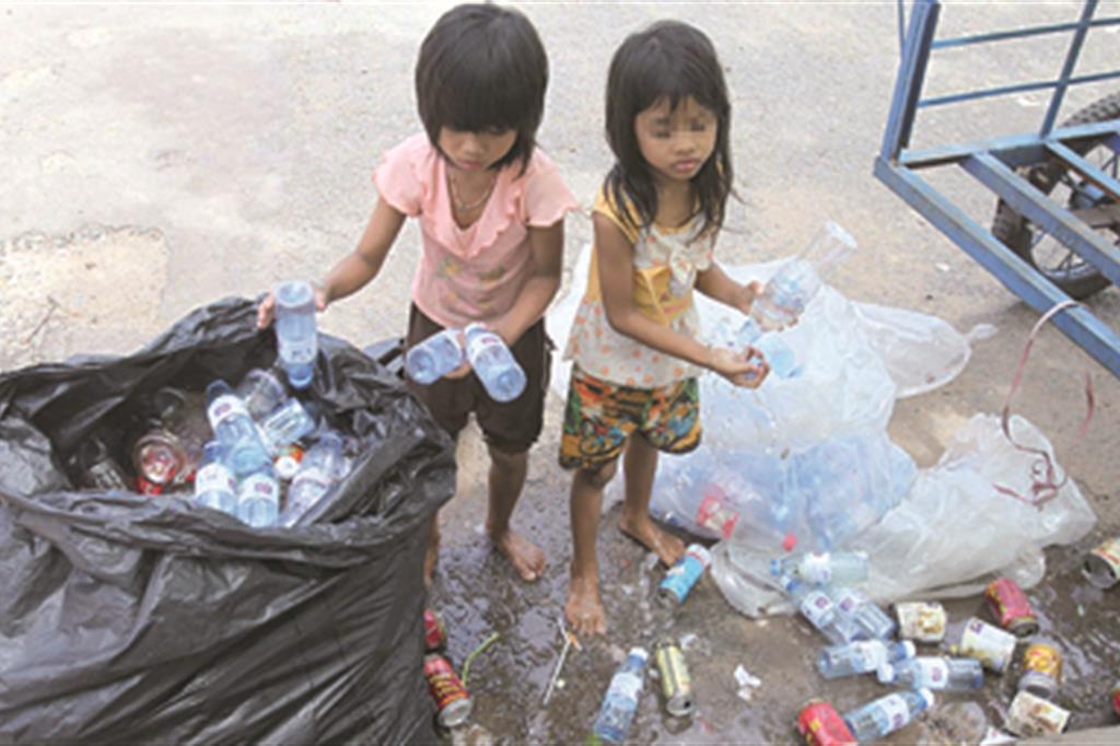 Due bambine raccolgono bottiglie  alla periferia  di Hanoi: provengono dall’Asia molte delle minorenni sfruttate in Gran Bretagna dai trafficanti di persone