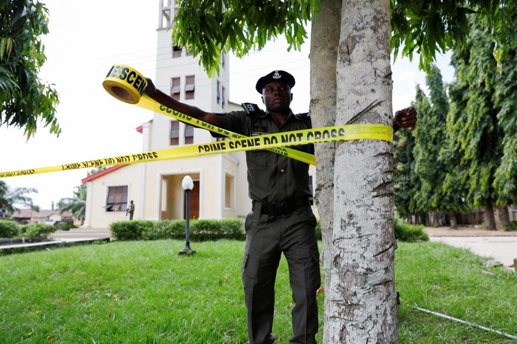 Un poliziotto delimita la scena del crimine, dopo la strage nella chiesa di San Francesco a Owo il 6 giugno 2022