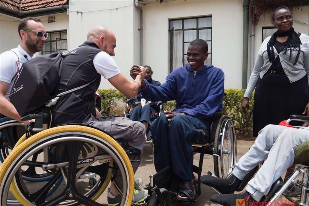 Danilo Ragona, in carrozzella mentre stringe la mano a un giovane disabile del Kenya, è uno dei promotori dell'iniziativa di solidarietà
