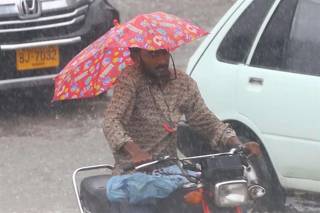 Un uomo si ripara dalla pioggia dei monsoni a Karachi in Pakistan