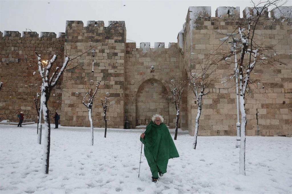 Un uomo cammina sulla neve vicino alla Porta di Jaffa nella Città Vecchia di Gerusalemme - Ansa