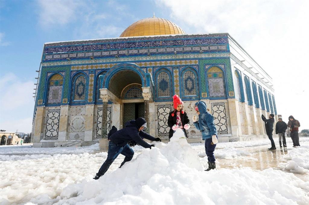 Bambini costruiscono un pupazzo davanti al Duomo della Roccia a Gerusalemme dopo una rarissima nevicata - Reuters