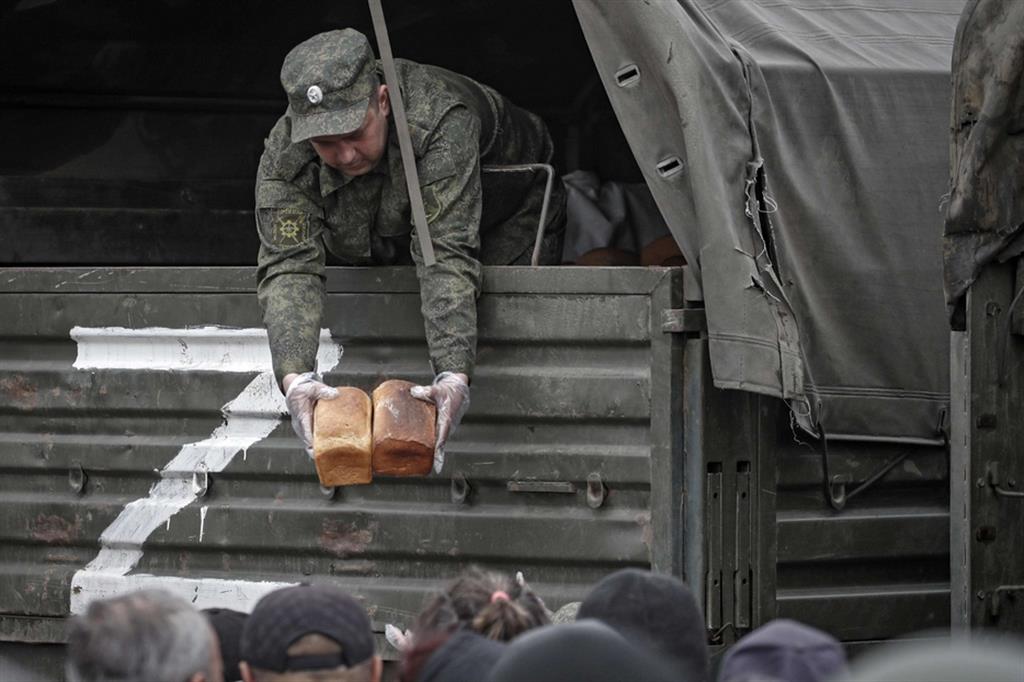 Un miliziano filorusso distribuisce pane alla popolazione di Mariupol, sotto occupazione ormai da settimane