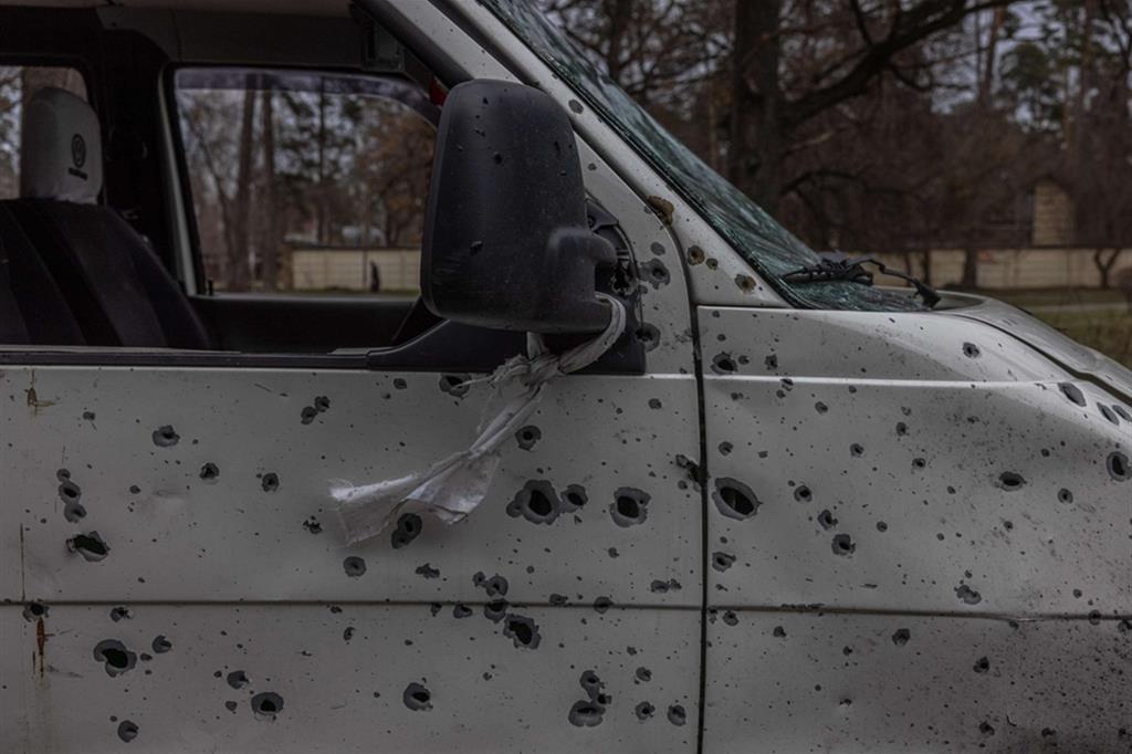 Un'auto crivellata di colpi a Bucha. Attaccato allo specchietto, un nastro bianco a indicare che a bordo c'erano civili disarmati - EPA/ANSA/ROMAN PILIPEY