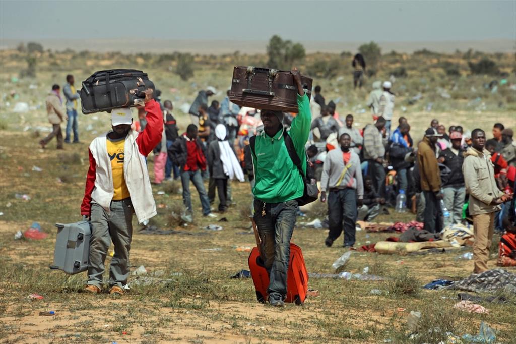 Profughi ghanesi in attesa di essere rimpatriati restano per ore in fila nel deserto vicino al campo di Choucha a Ras Jadir in Tunisa