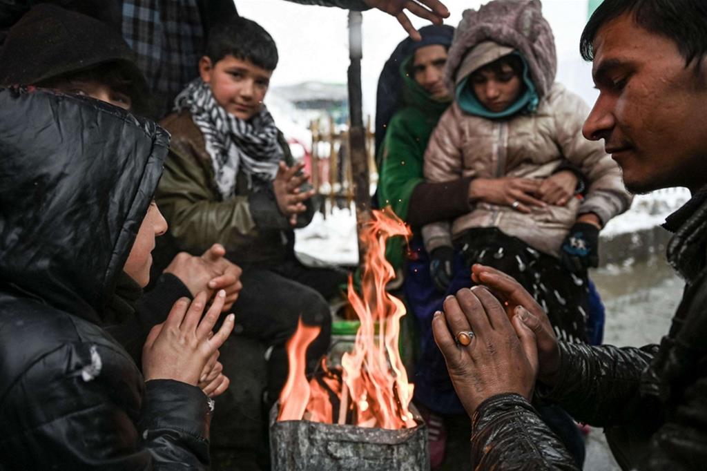 Una famiglia si riscalda con un fuoco: in questi giorni è arrivato il gelo a Kabul