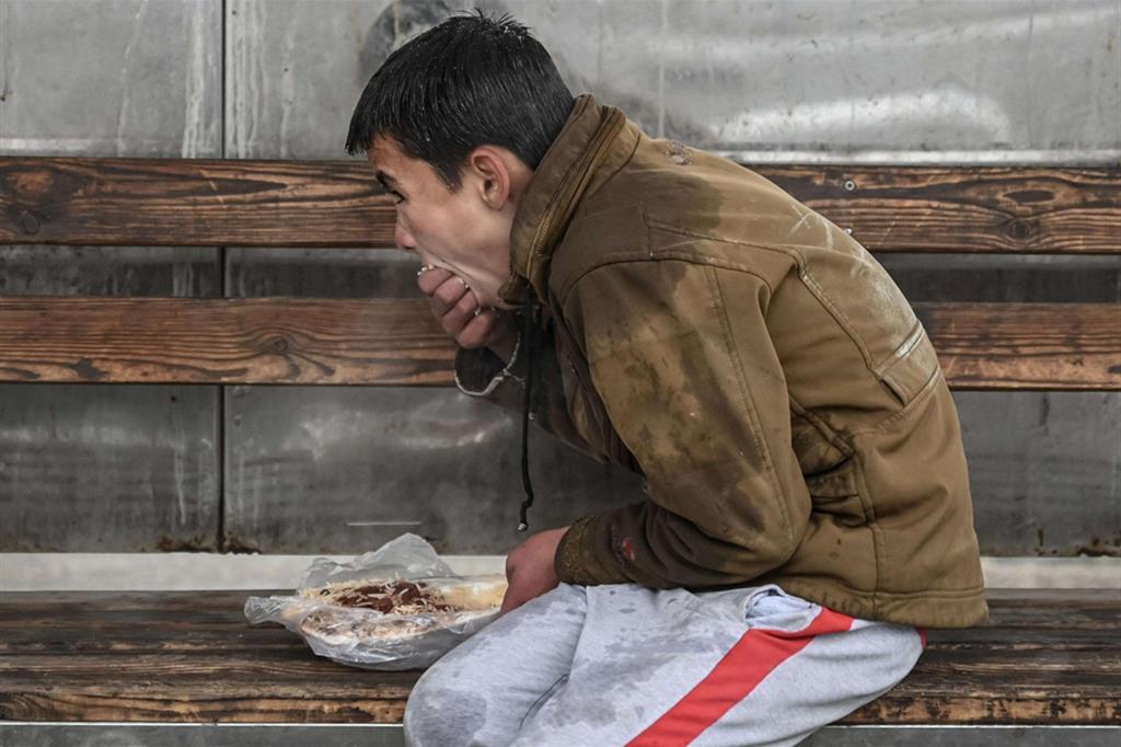 Un giovane mangia mentre attende il bus alla stazione di Kabul - Mohd RASFAN / AFP