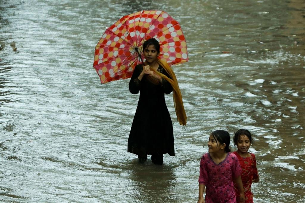 Bambini pakistani camminano in una strada allagata dalle piogge monsoniche a Peshawar
