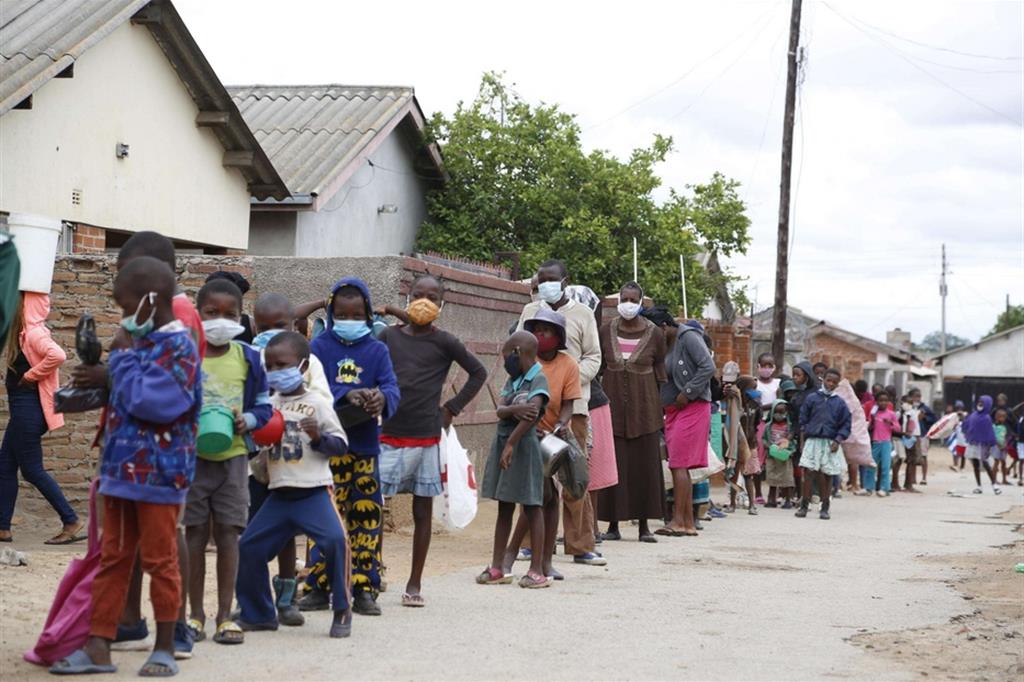 Adults and children line up for a food ration in the town of Chitungwiza: Zimbabwe has now become one of the poorest countries in Africa