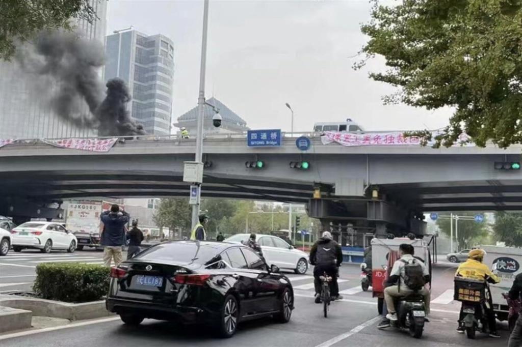 Uno striscione di protesa su un ponte di Pechino viene rimosso dalle autorità