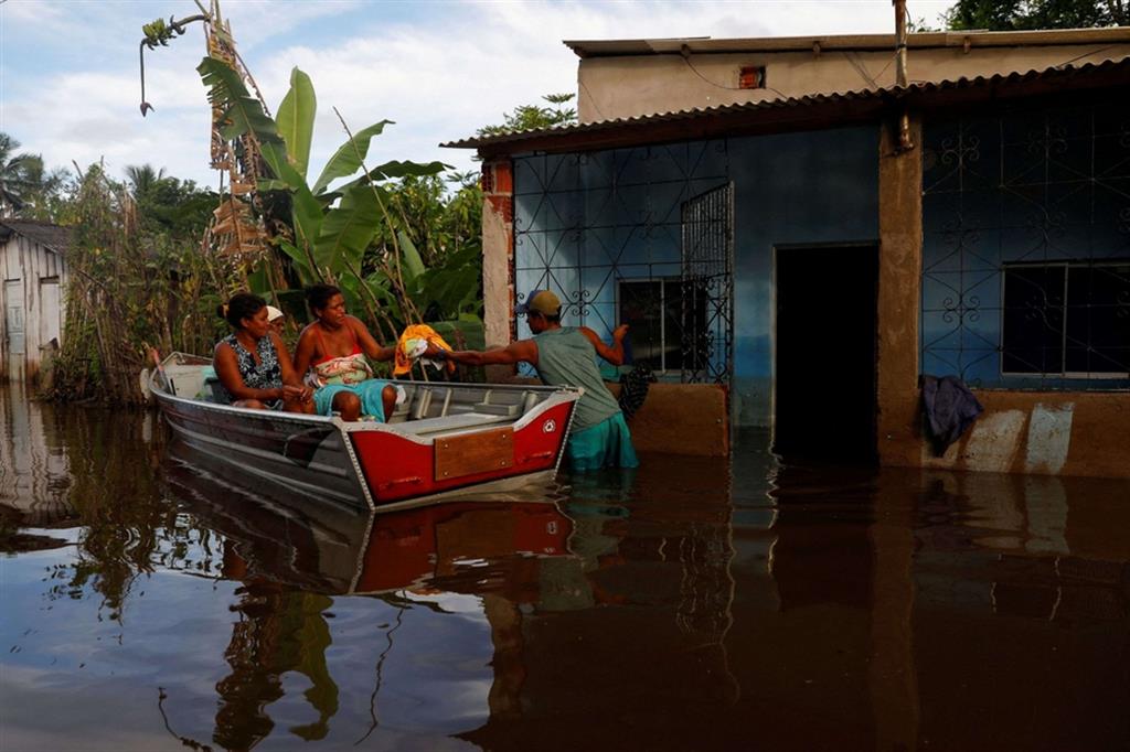 Sergio da Silva dos Santos recupera vestiti da una casa alluvionata, a Sambaituba nello Stato brasiliano di Bahia - REUTERS/Amanda Perobelli