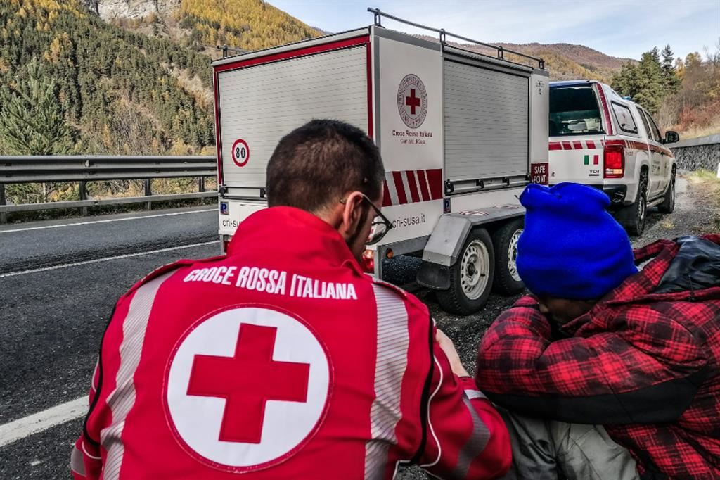 Il centro Caritas a Ventimiglia; a destra un operatore della Croce rossa aiuta un giovane somalo a Claviér
