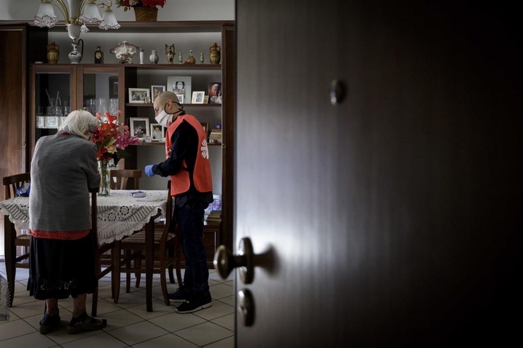 Un volontario della Caritas aiuta una persona anziana a domicilio durante la pandemia Covid