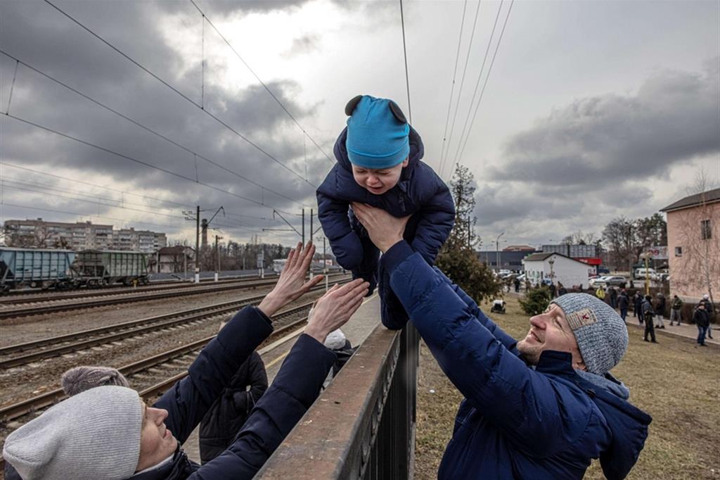 Un padre porge il figlio alla moglie in partenza dalla stazione di Irpin per Kiev