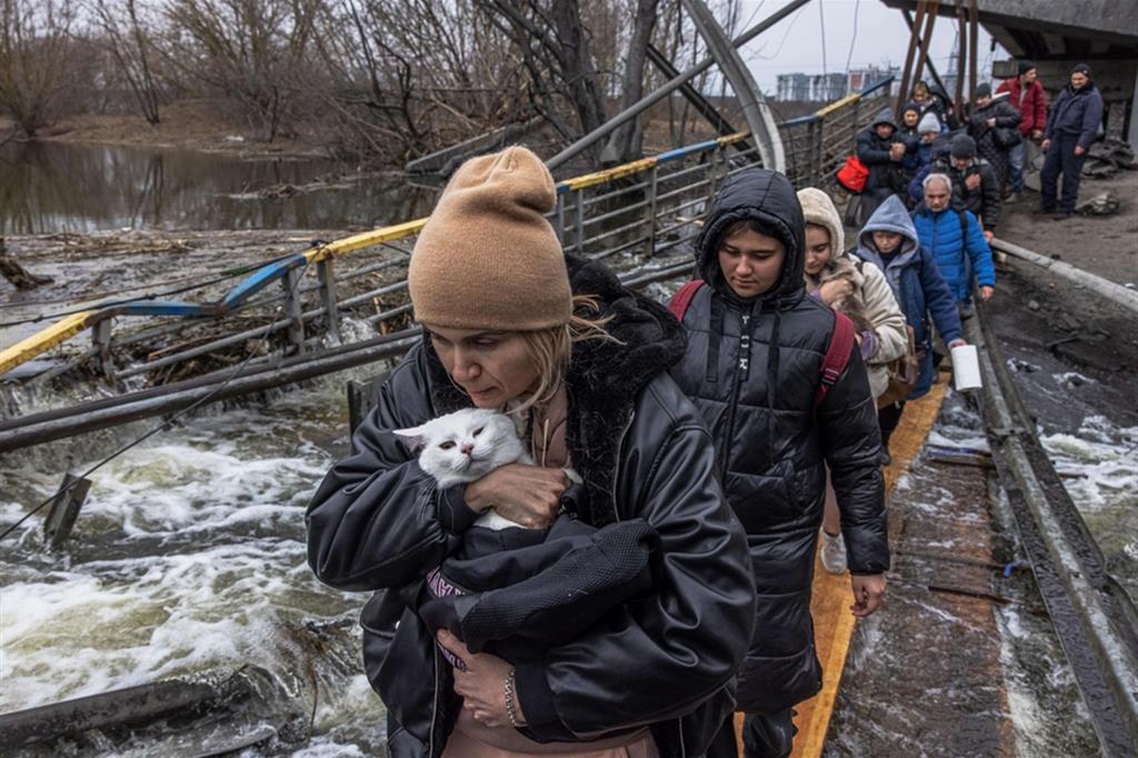 Una donna tiene stretto il suo gatto mentre attraversa un ponte distrutto dai bombardamenti a Irpin, nell'Oblast di Kiev - Ansa