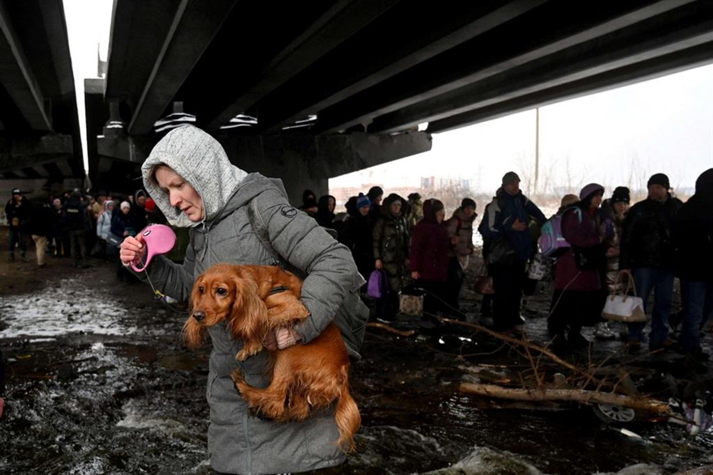 Con il cane in braccio per attraversare quel che resta del ponte bombardato a Irpin, città nell'Oblast di Kiev - Ansa