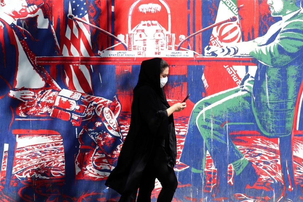 Una donna iraniana cammina davanti a un murale