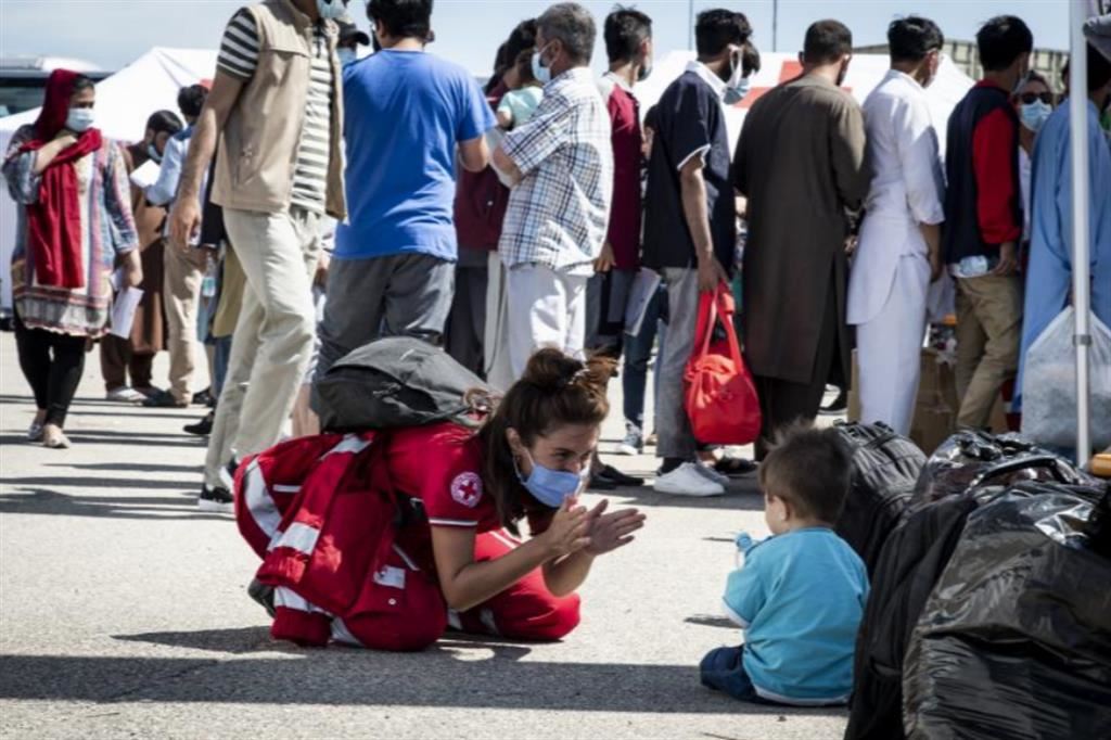 Operatrice della Croce rossa Italiana accoglie un piccolo profugo proveniente dall'Afghanistaninsieme alla sua famiglia