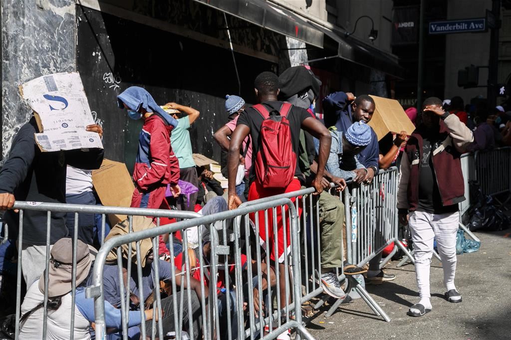 Migranti in fila davanti all'ingresso del centro di accoglienza del Roosevelt Hotel a New York