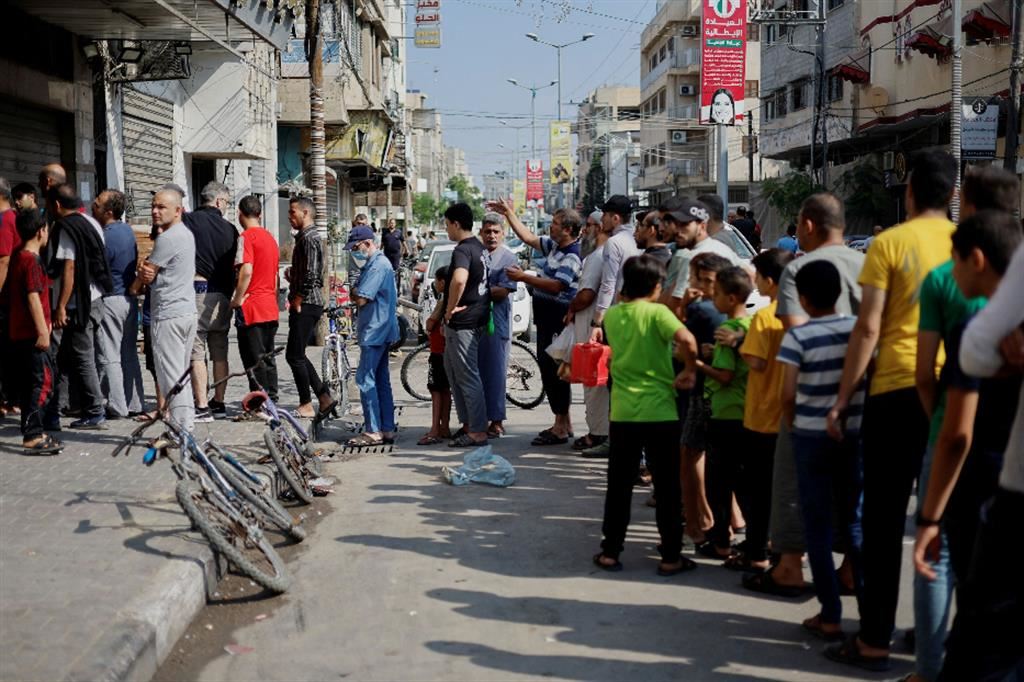Palestinesi aspettano di comprare il pane fuori da un panificio a Khan Younis