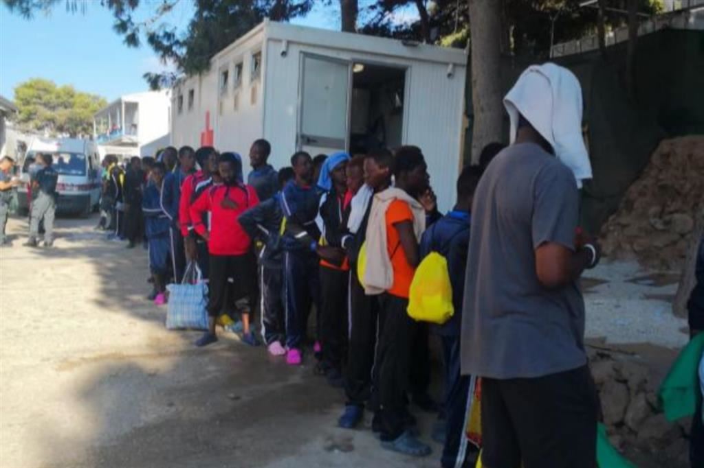 Migranti in fila, in attesa di essere trasferiti con l’autobus da Porto Empedocle