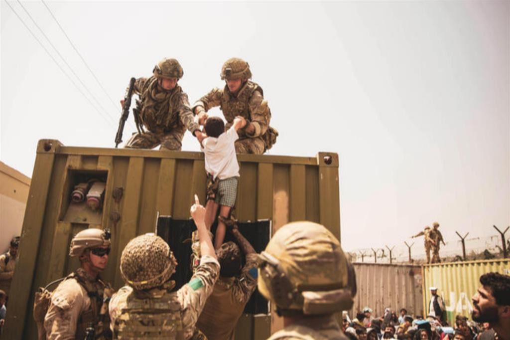 Militari britannici e americani sollevano un bimbo durante l’assedio all’aeroporto di Kabul da parte dei civili in fuga