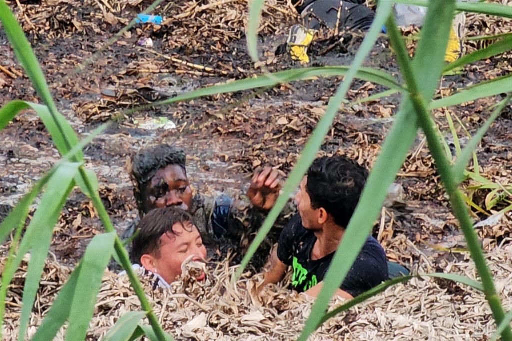 Migranti nel fango della sponda messicana del Rio Bravo