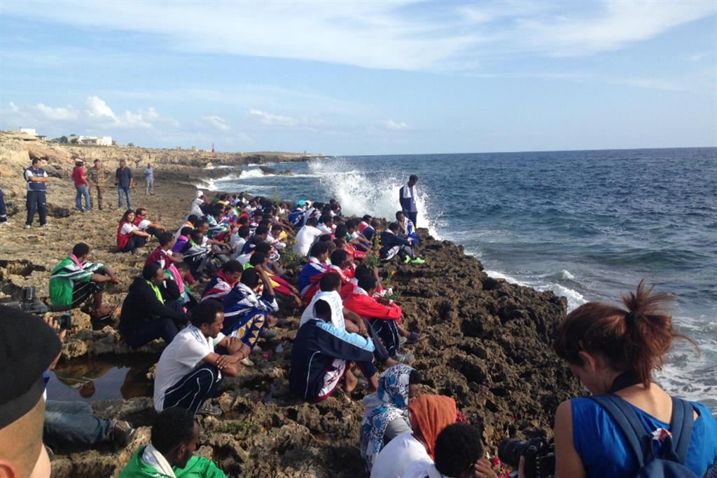 Chi non è potuto andare ad Agrigento per la cerimonia commemora i morti seduto sugli scogli di Lampedusa davanti al mare