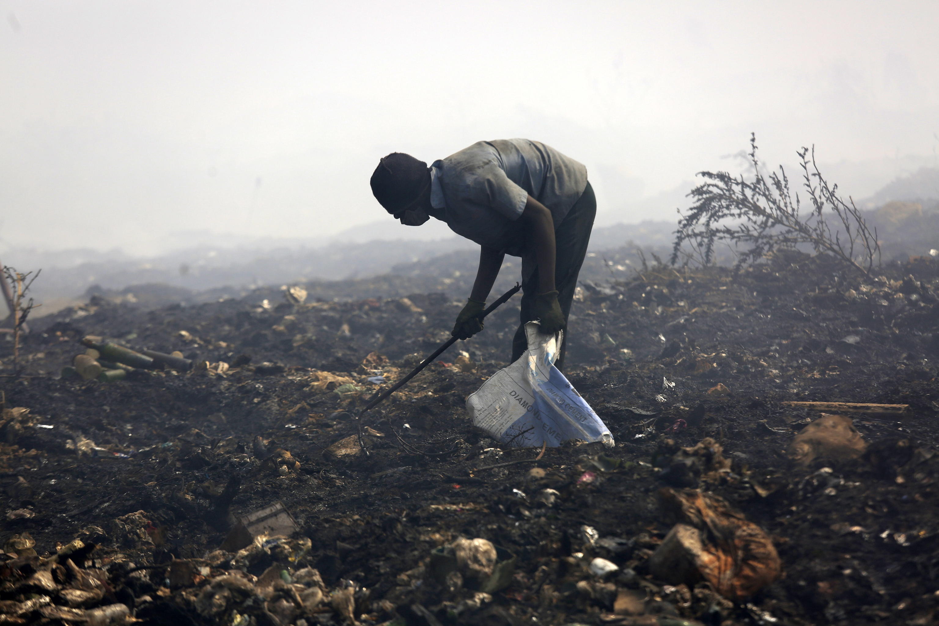 Un uomo cerca qualcosa da vendere in un campo bruciato ad Harare in Zimbabwe