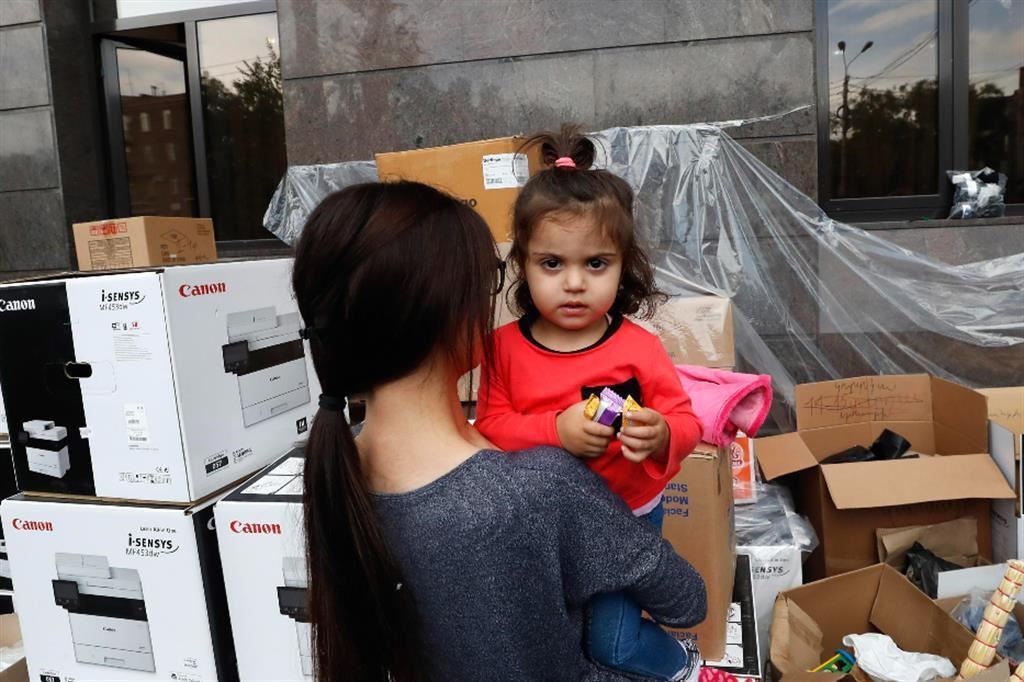Una volontaria tiene in braccio una piccola rifugiata armena in un punto di assistenza organizzato a Erevan