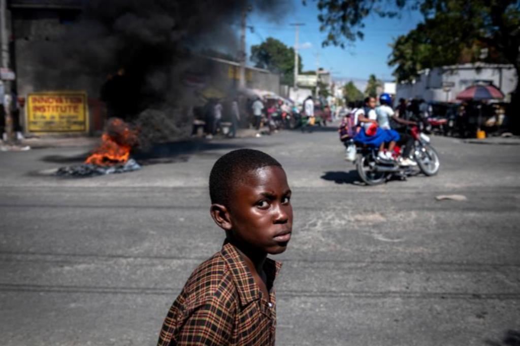 Un ragazzino assiste agli scontri di piazza vicino alla residenza del primo ministro a Port-au-Prince