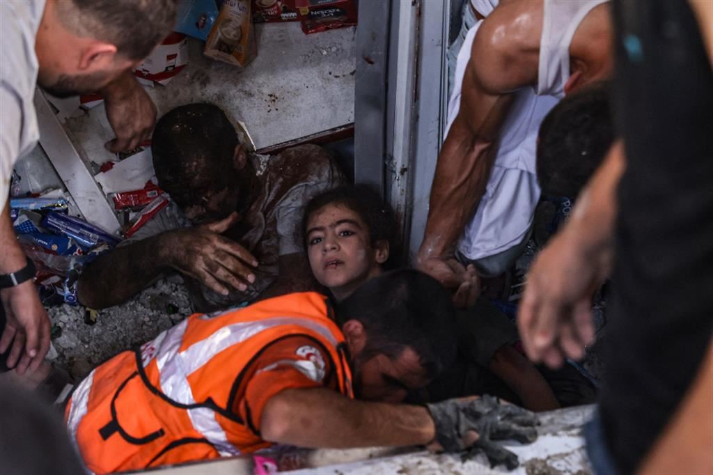 Soccorritori estraggono una ragazzina ferita e un uomo delle macerie di un supermercato nel campo profughi di Khan Younis, Striscia di Gaza meridionale, oggi 25 ottobre