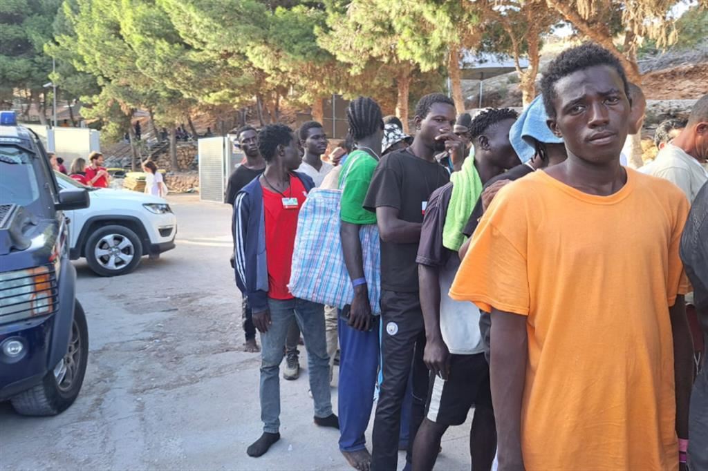 Migranti escono dall'hotspot di Lampedusa per essere imbarcati per Porto Empedocle
