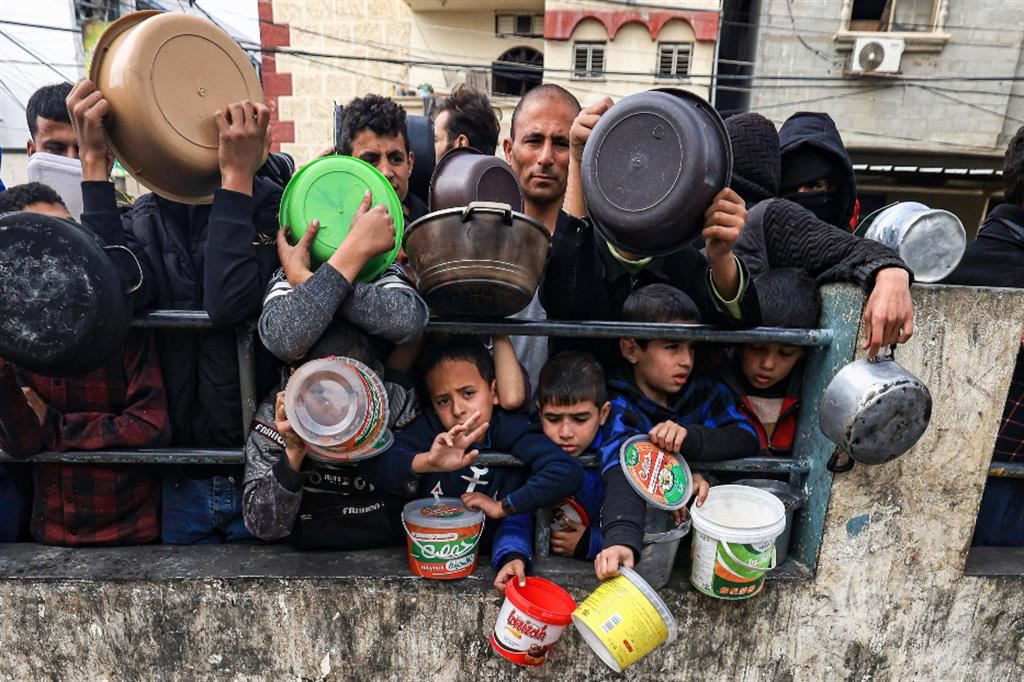 Palestinesi in attesa di ricevere cibo da un'agenzia umanitaria in un campo profughi di Rafah, nell'estremo sud della Striscia di Gaza