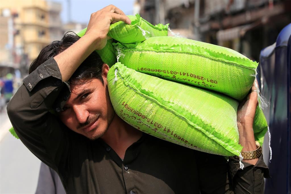 Un uomo porta sacchi di grano distribuiti gratuitamente dal governo in Pakistan