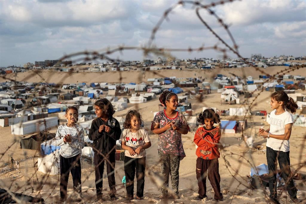 Bambini dietro una rete di filo spinato lungo il confine egiziano in un campo di sfollati a Rafah