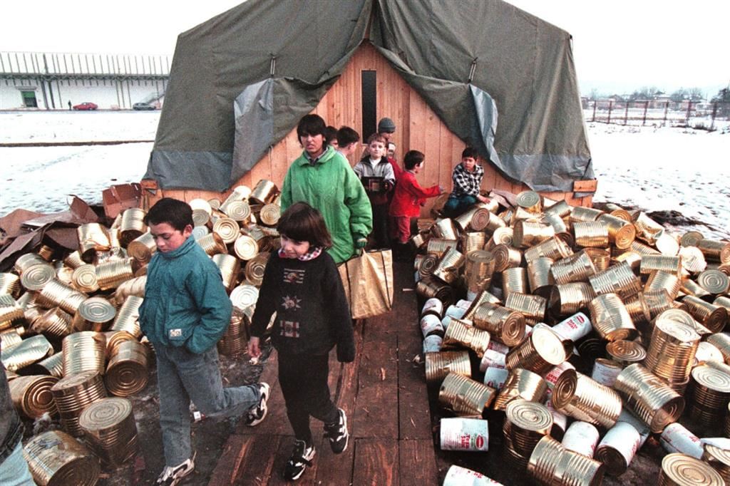 Bambini albanesi del Kosovo escono da una scuola di fortuna, tra pile di cibo in scatola, a Sarajevo. Foto scattata nel gennaio 1999