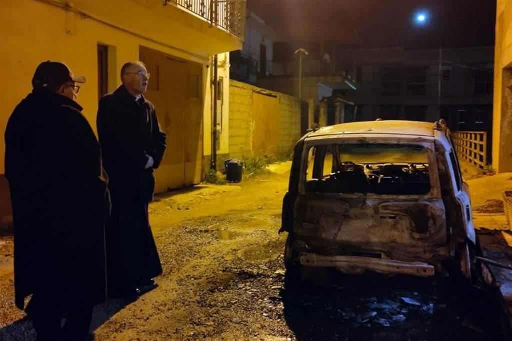 Don Gianni Rigoli e il vescovo Giuseppe Alberti a Varapodio, alcuni giorni fa, di fianco alla carcassa dell'auto