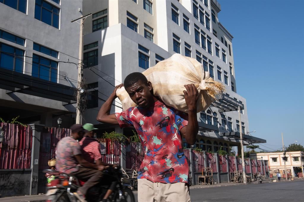 Con un sacco di patate sulle spalle, un uomo si arrischia nel Champs de Mars, la piazza principale della capitale Port-au-Prince