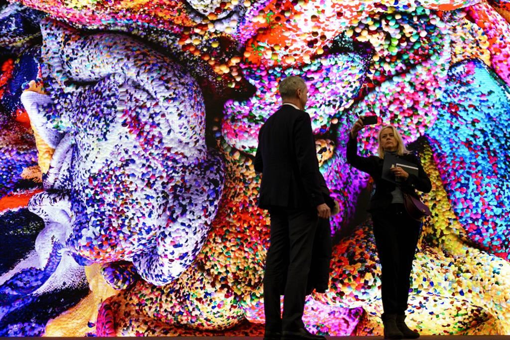 Davos, 54esimo forum economico, selfie davanti a uno schermo con immagini generate da A.I..
