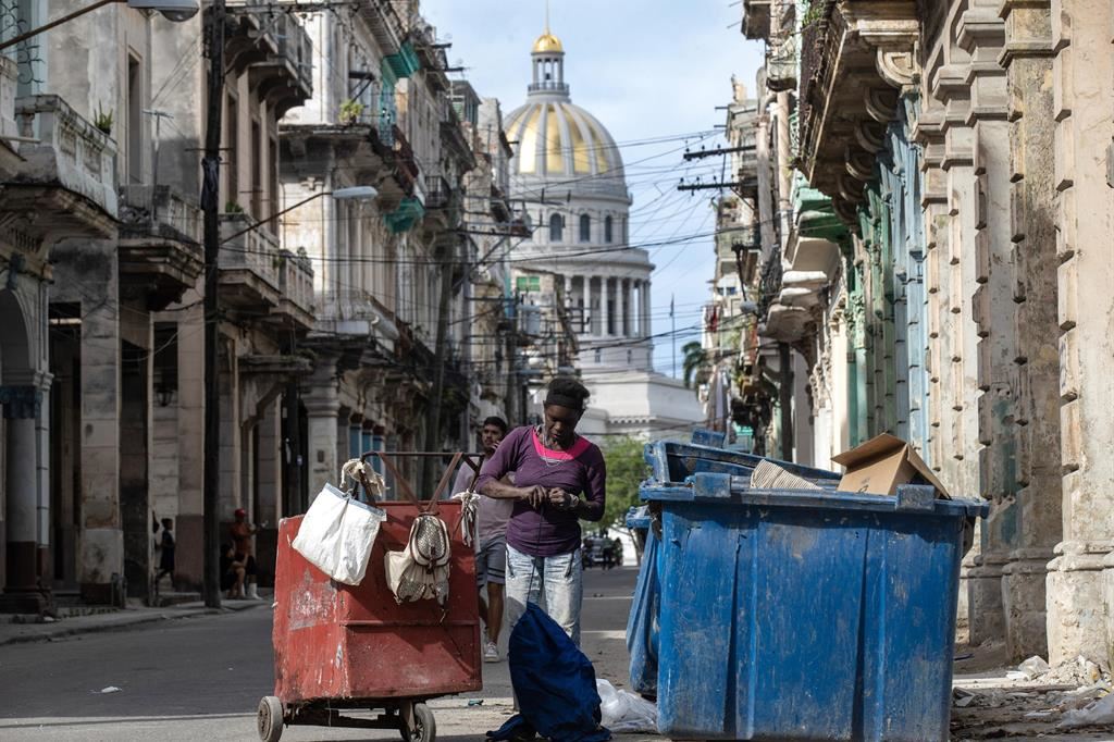 All'alba, una donna rovista fra i cassonetti nel centro dell'Avana in cerca di qualcosa da mangiare o da rivendere